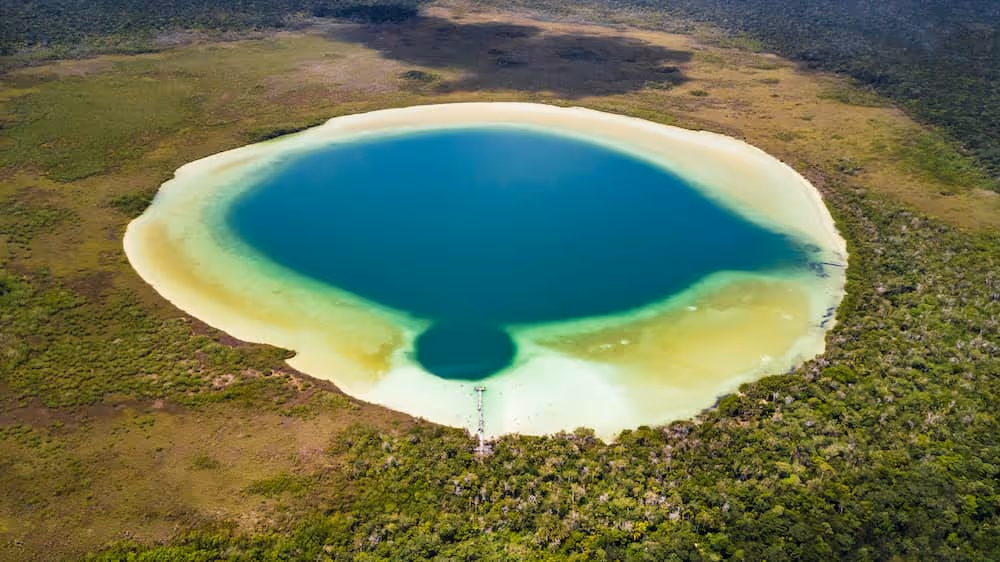 Emerald green Kan Luum lagoon reflecting the sky, a natural oasis near Tulum