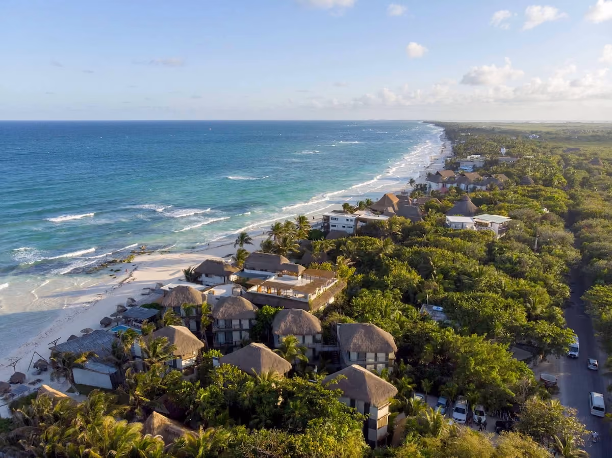 A pristine beach in Tulum with turquoise waters and white sand, showcasing the beauty that attracts those who choose buying property in Tulum