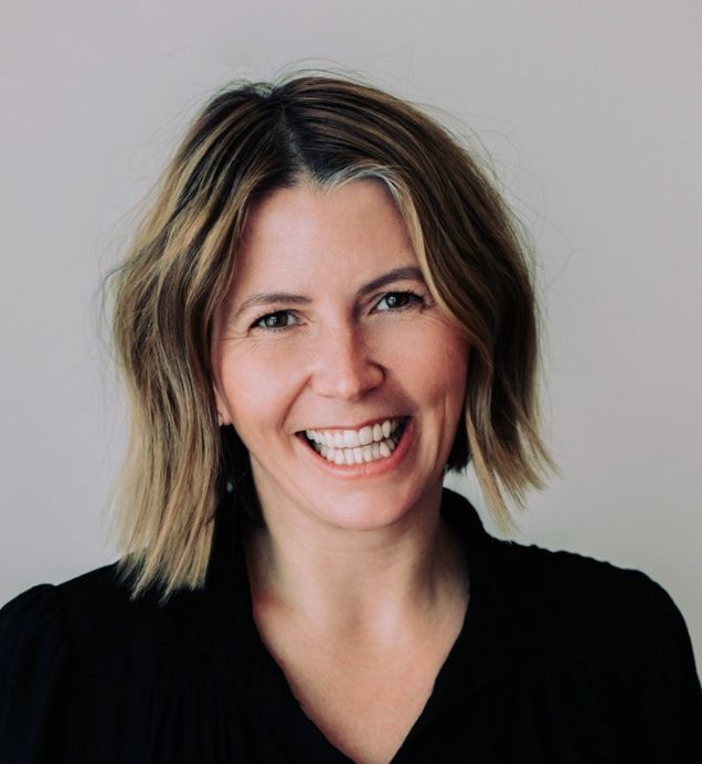 Michelle Kuly, Founder & Lead Strategist — Smiling person with short blonde wavy hair wearing a black top, against a neutral background