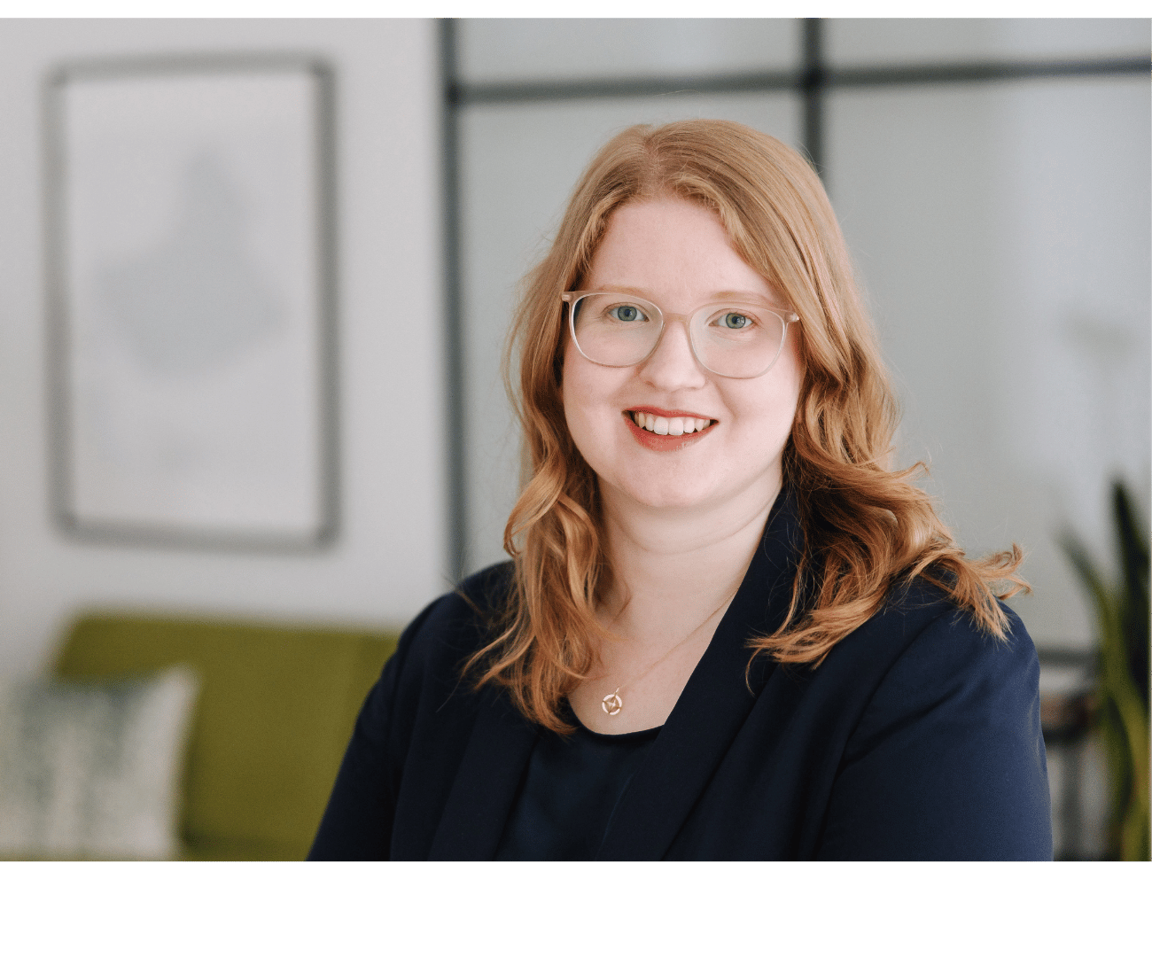 Porträt von Julia Reis - Gründerin und Chefberaterin von Julia Reis Consulting. Sie hat langes rotes Haar, trägt ein dunkles Oberteil, eine Brille und lächelt in die Kamera