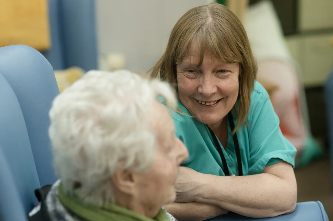 Care worker smiling as she supports an elderly resident