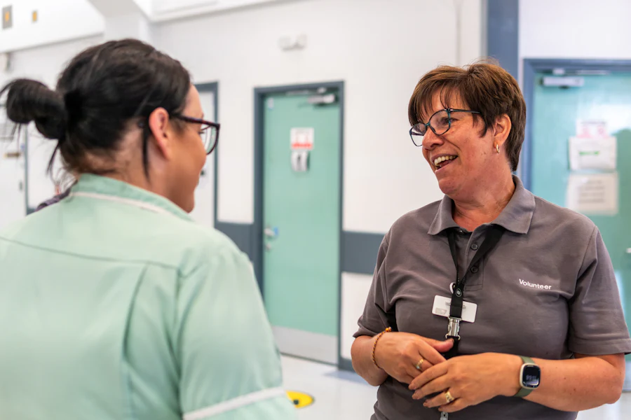 Two care workers talking in a hallway between shifts