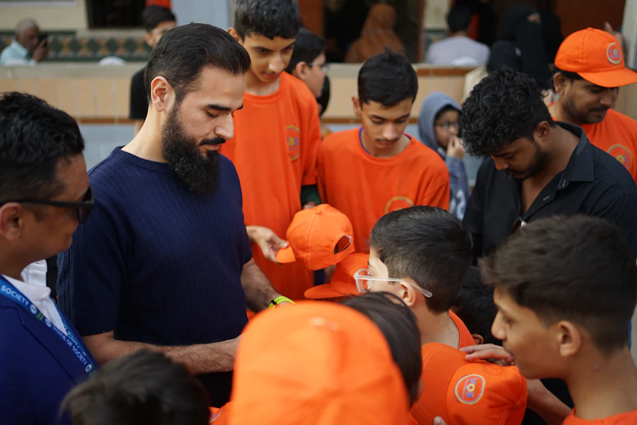 Community programme leader handing out caps to young volunteers