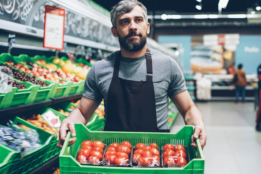 Grocery store worker carrying a crate of fresh produce