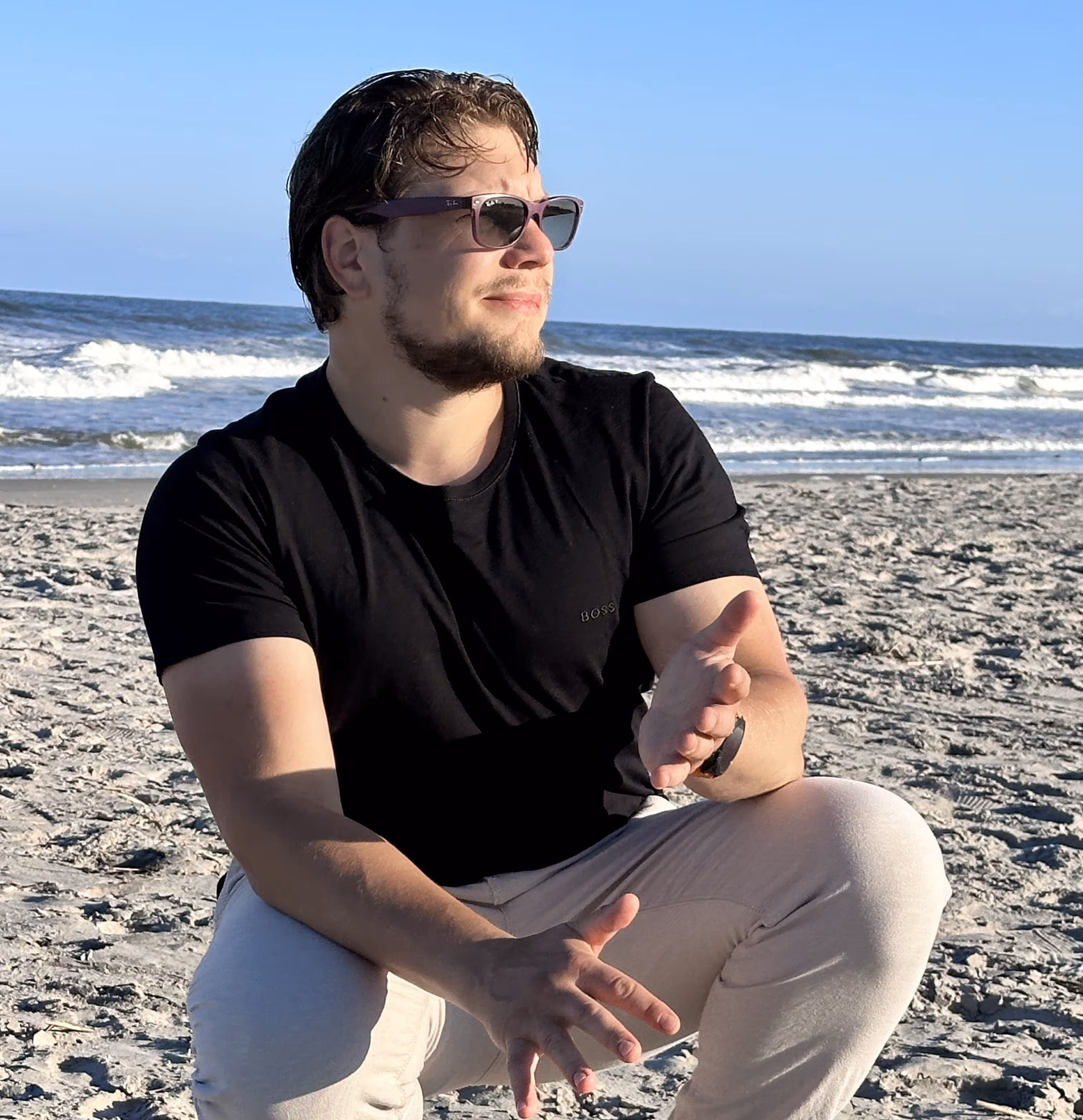 Anton is cleaning his hands of the sand while looking at the horizon. The Atlantic Ocean is in the background.