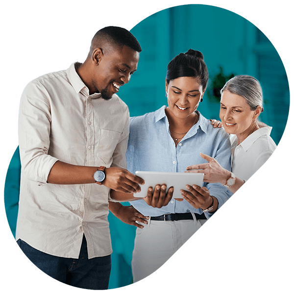 Three colleagues looking at a tablet together, smiling and discussing content.