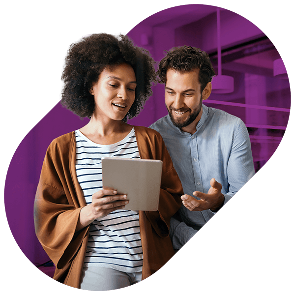 Smiling man and woman looking at a tablet together in a modern office setting.