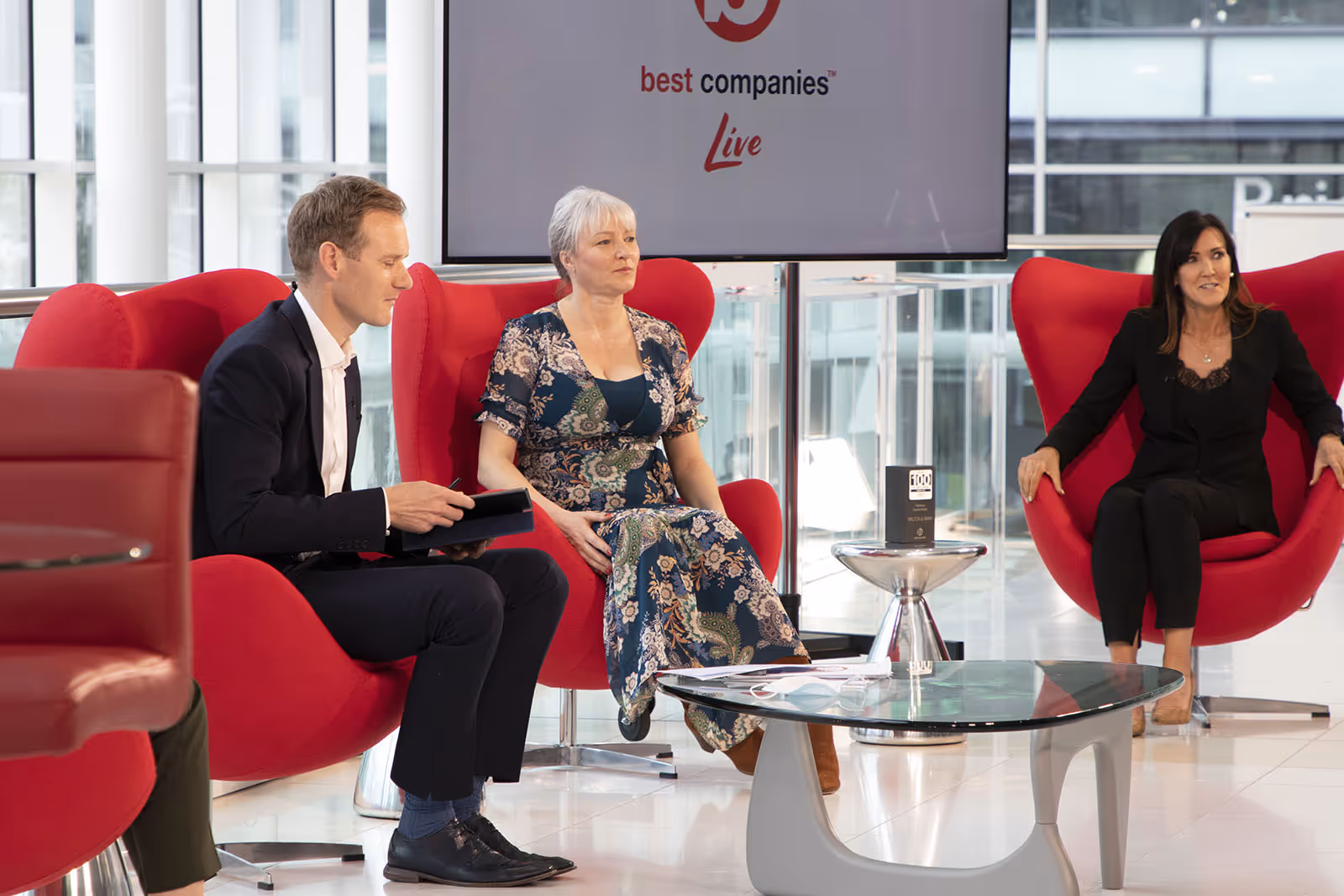 TV Presenter Dan Walker with Community Trust CEO Emma Ratzer MBE and People and brand Director of Wilton and Bain Claire Elliott on the set of Best Companies Live
