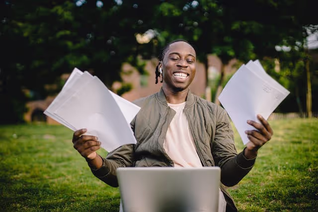 male student holding papers and smiling