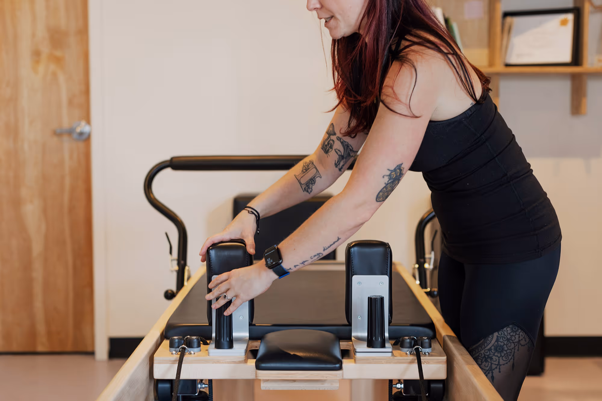 Female pilates instructor sets up reformer for her clients