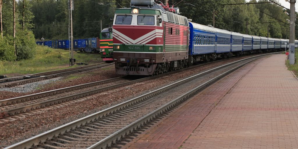 a train traveling down train tracks next to a forest