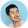 Smiling man with short dark hair and stubble against a light blue background.