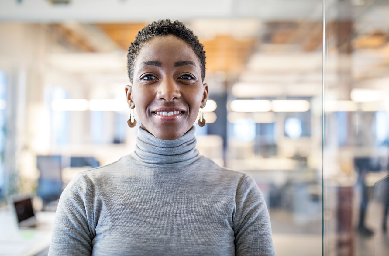 A woman looking directly at the camera with a smile in an office setting