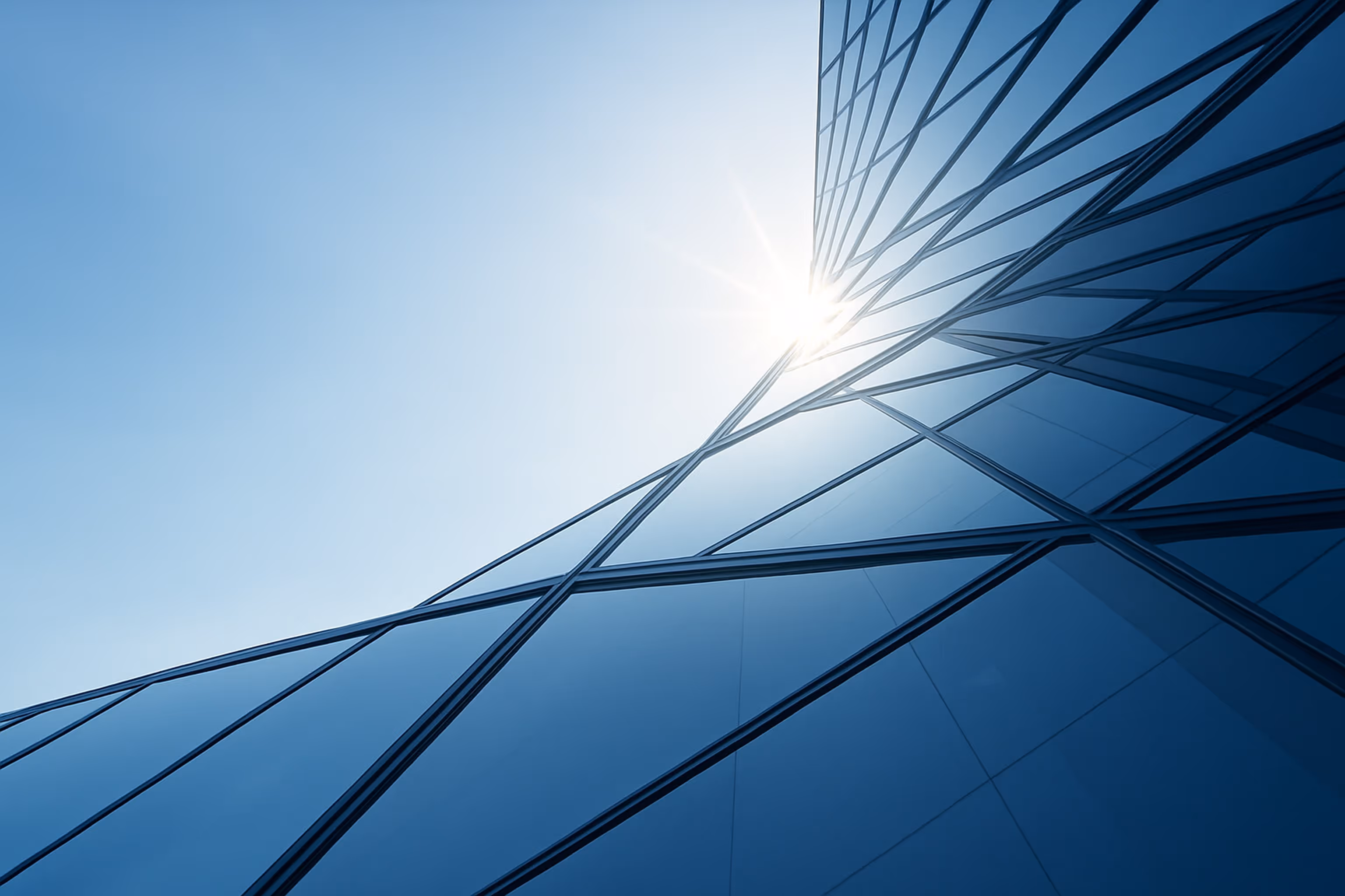 Sonneneinstrahlung auf die Glasfassade eines modernen Hochhauses mit blauem Himmel im Hintergrund.