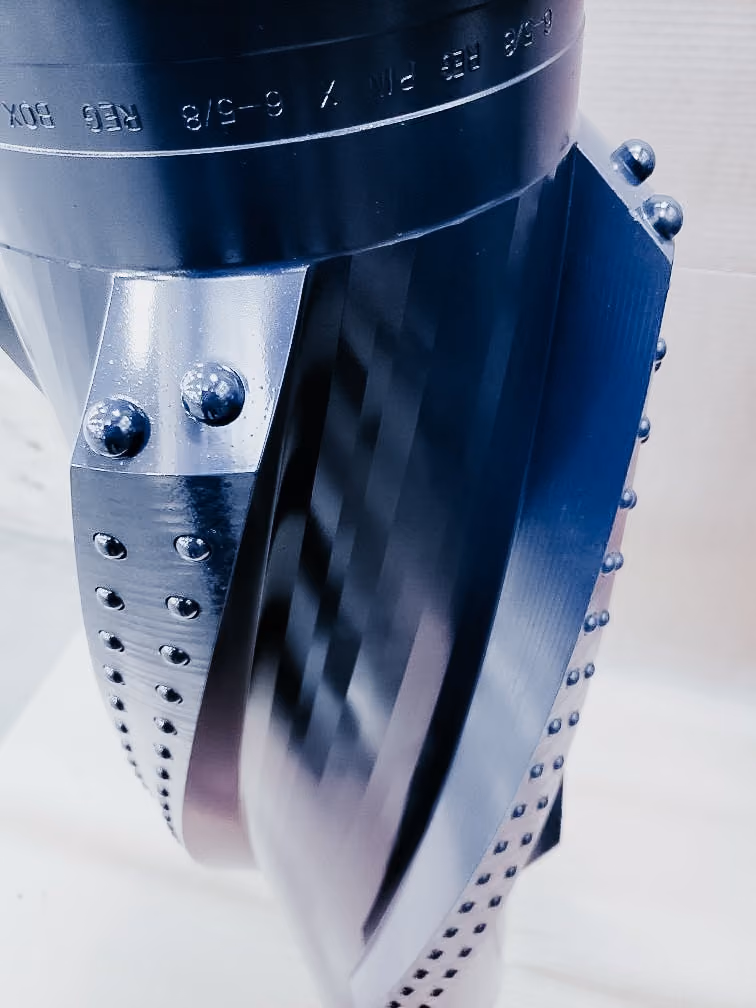 Close-up view of a metallic spiral blade stabilizer with rows of rivets on its sides and engraved markings on the upper part.