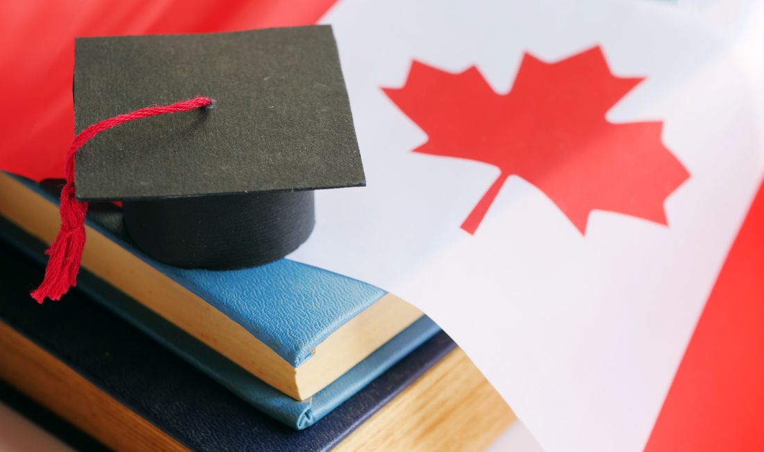 A Graduation Cap and Canadian Flag Laying on a Stack Of Books