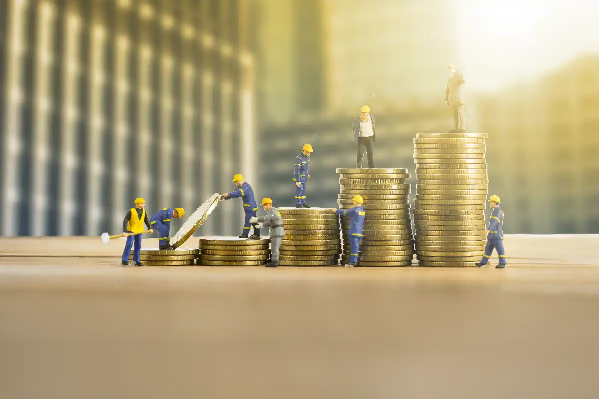 Bonequinhos em miniatura sobre pilhas de moedas