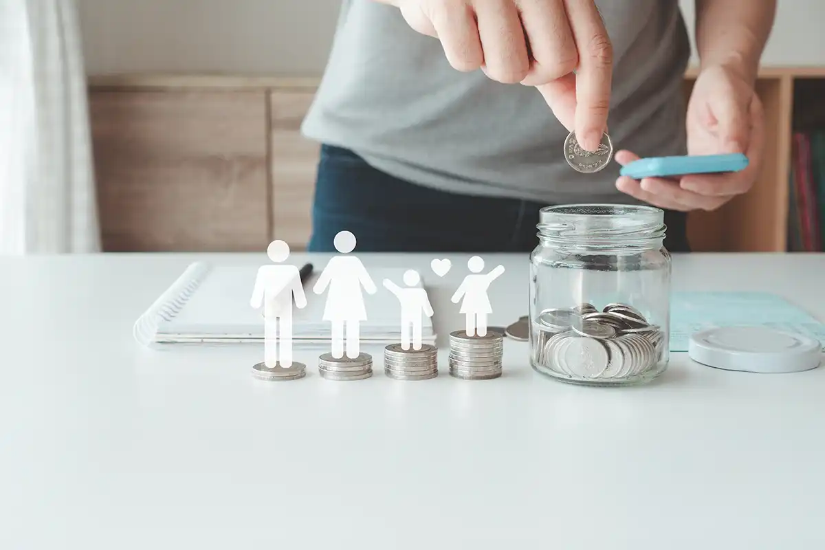 Uma família de bonequinhos de papel sobre pilhas de moedas.