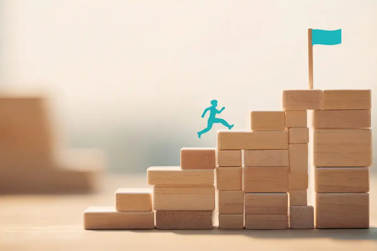 Um bonequinho de papel subindo uma escada de blocos de madeira.