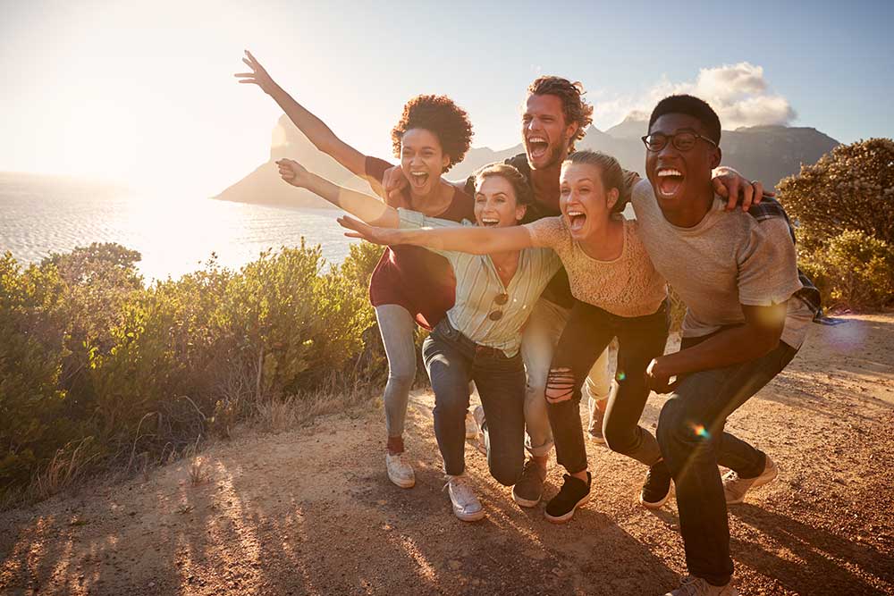 Foto de um grupo de pessoas se abraçando em uma trilha ao ar livre.