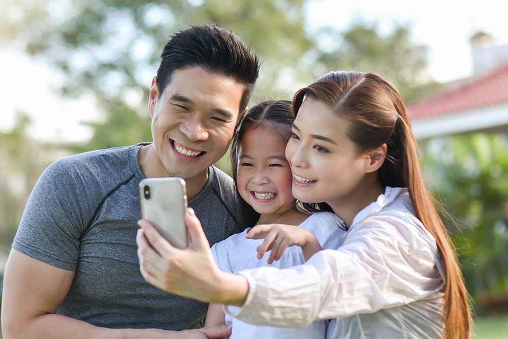 Foto de uma família se exercitando ao ar livre e olhando um smartphone.