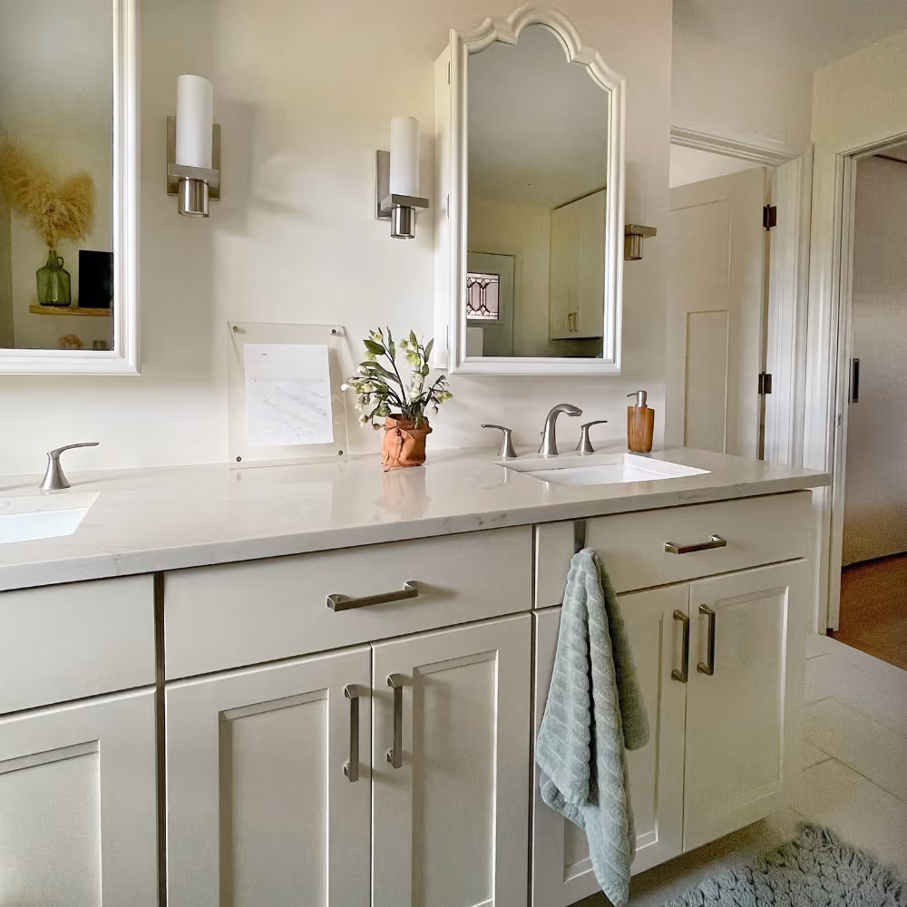 Double vanity bathroom with white cabinets, wall mirrors, brushed nickel fixtures, and a green towel.