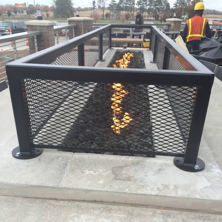 Metal fabricated black railing with grate enclosing a coal fire pit