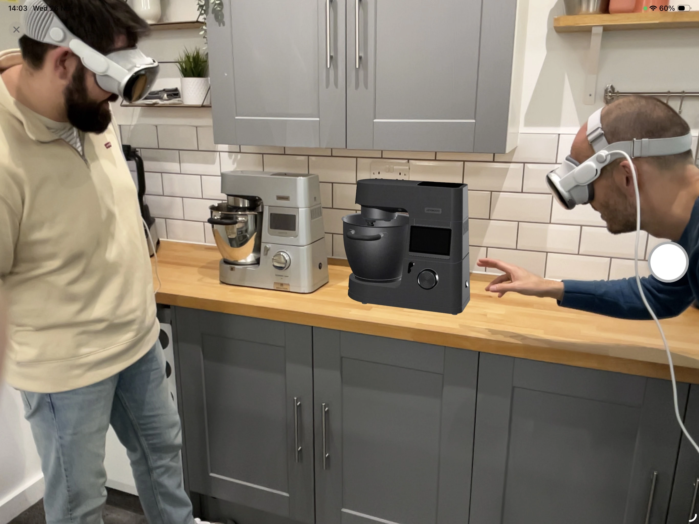 Two designers wearing Apple Vision Pro headsets looking at an AR model of a standing mixer on a kitchen counter.