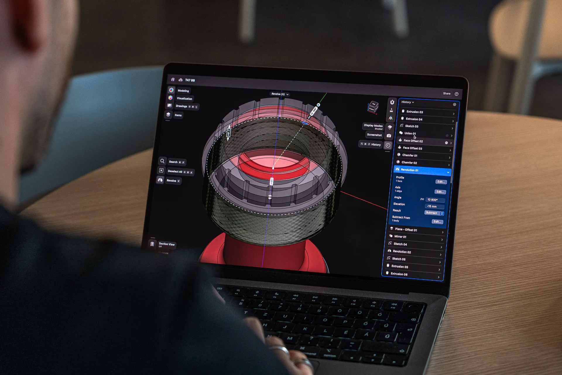 A designer working on a detailed mechanical model in Shapr3D on a laptop screen.
