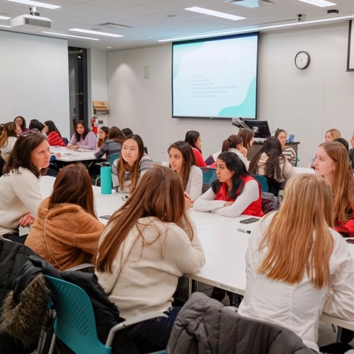 Women having a discussion with an event speaker at a table.