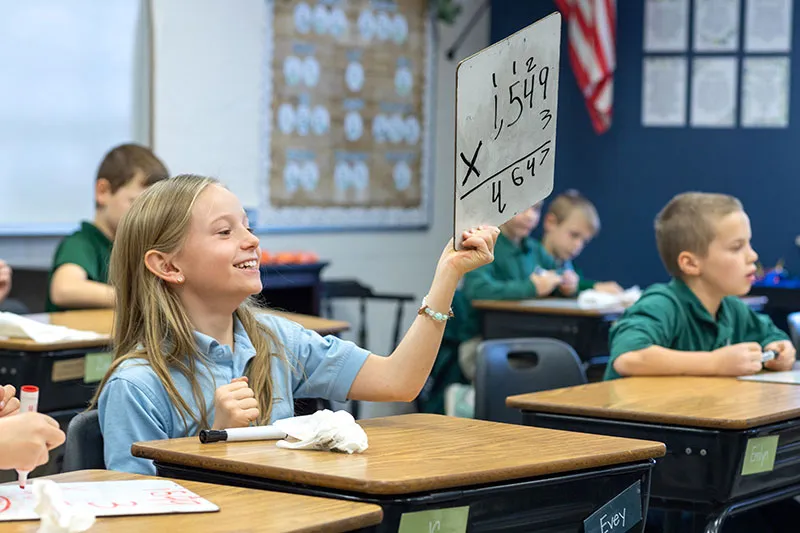 girl raising whiteboard with math problem