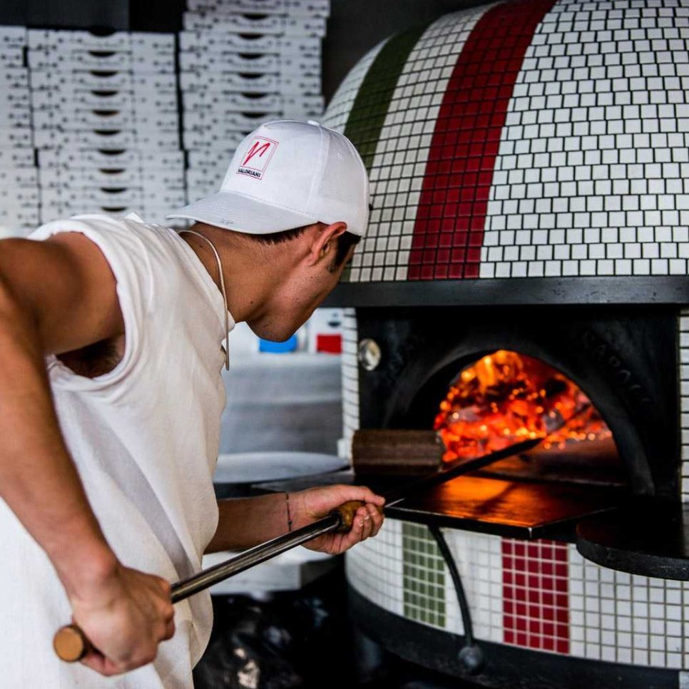 A pizzaiolo loading the wood-fired oven at 400 Gradi