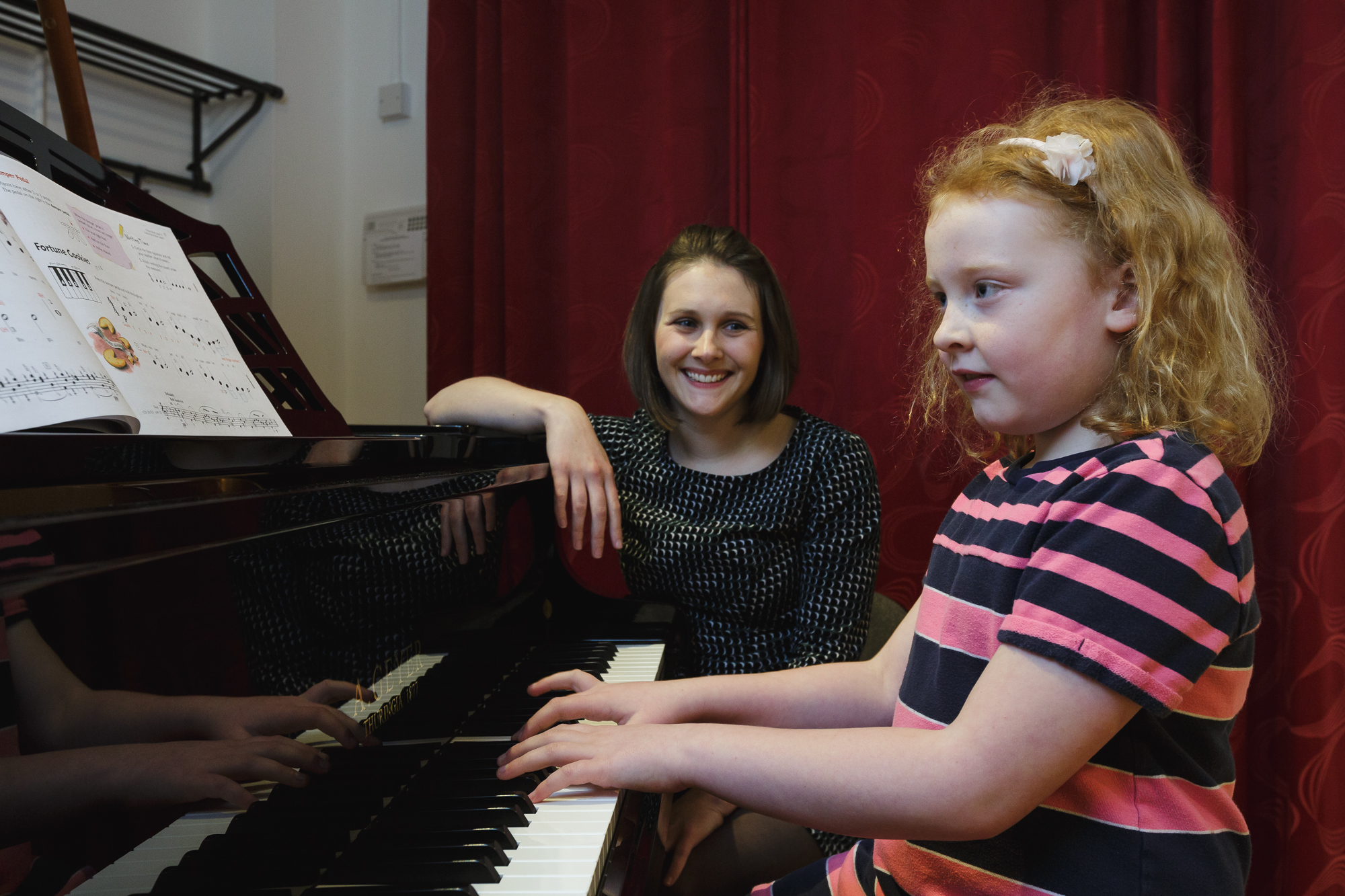 Bethan Scolding smiles as a young pupil plays the piano