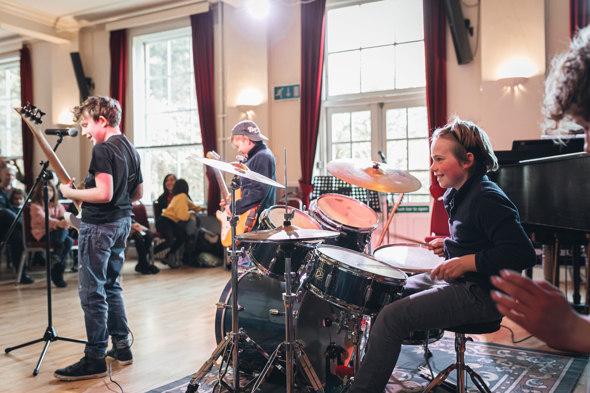 Young musicians on electric guitar, bass and drums performing at a Greenwich Music School student concert