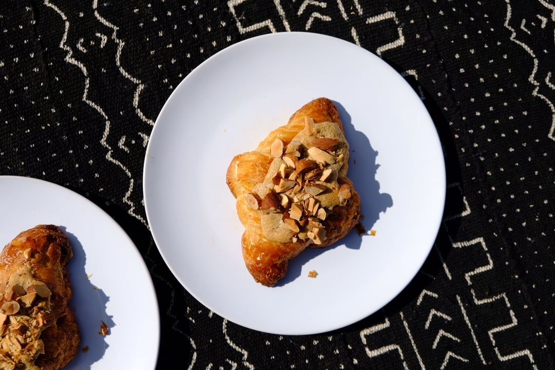 hand reaching for a cup of coffee and cardamom bun