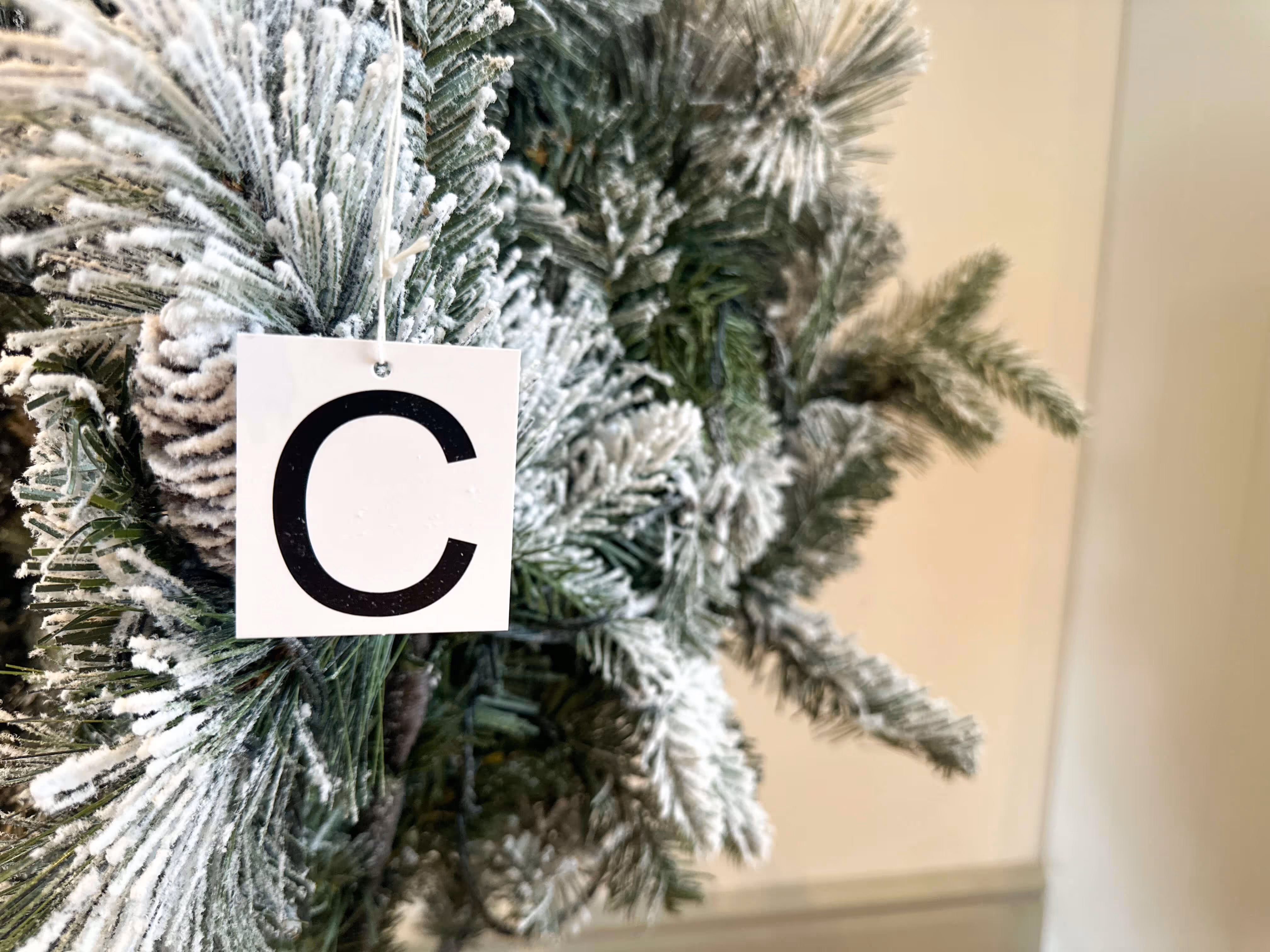 A person assembling a pre-lit snow flocked Christmas tree that comes in three labeled parts