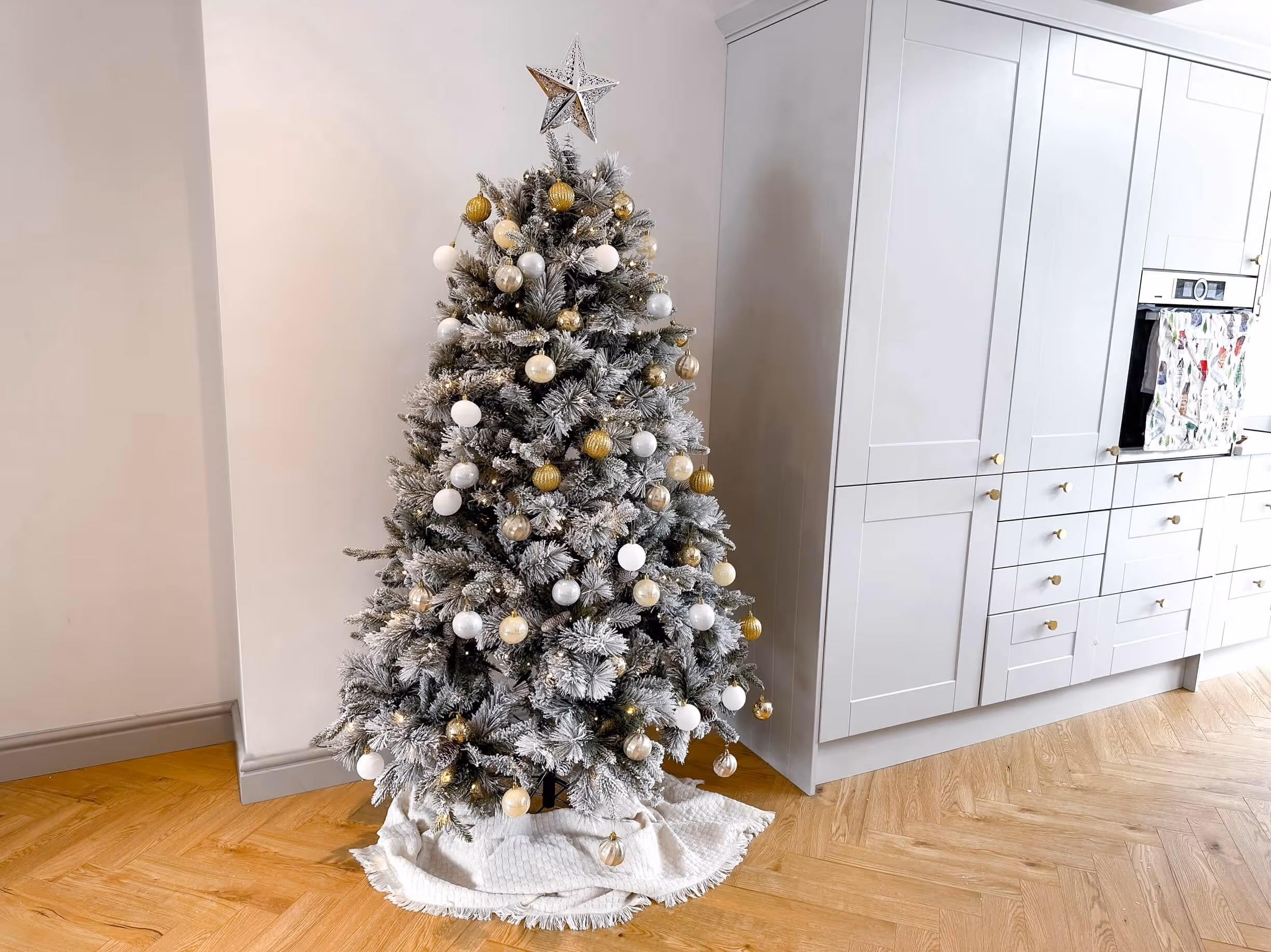 fluffing and shaping the snow-dusted branches of the artificial Christmas tree to make it look fuller and more realistic.