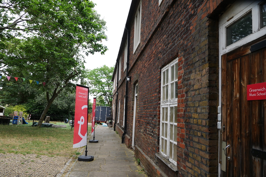 The brick exterior of The Stables at Charlton House, with Greenwich Music School signs beside the entrance.