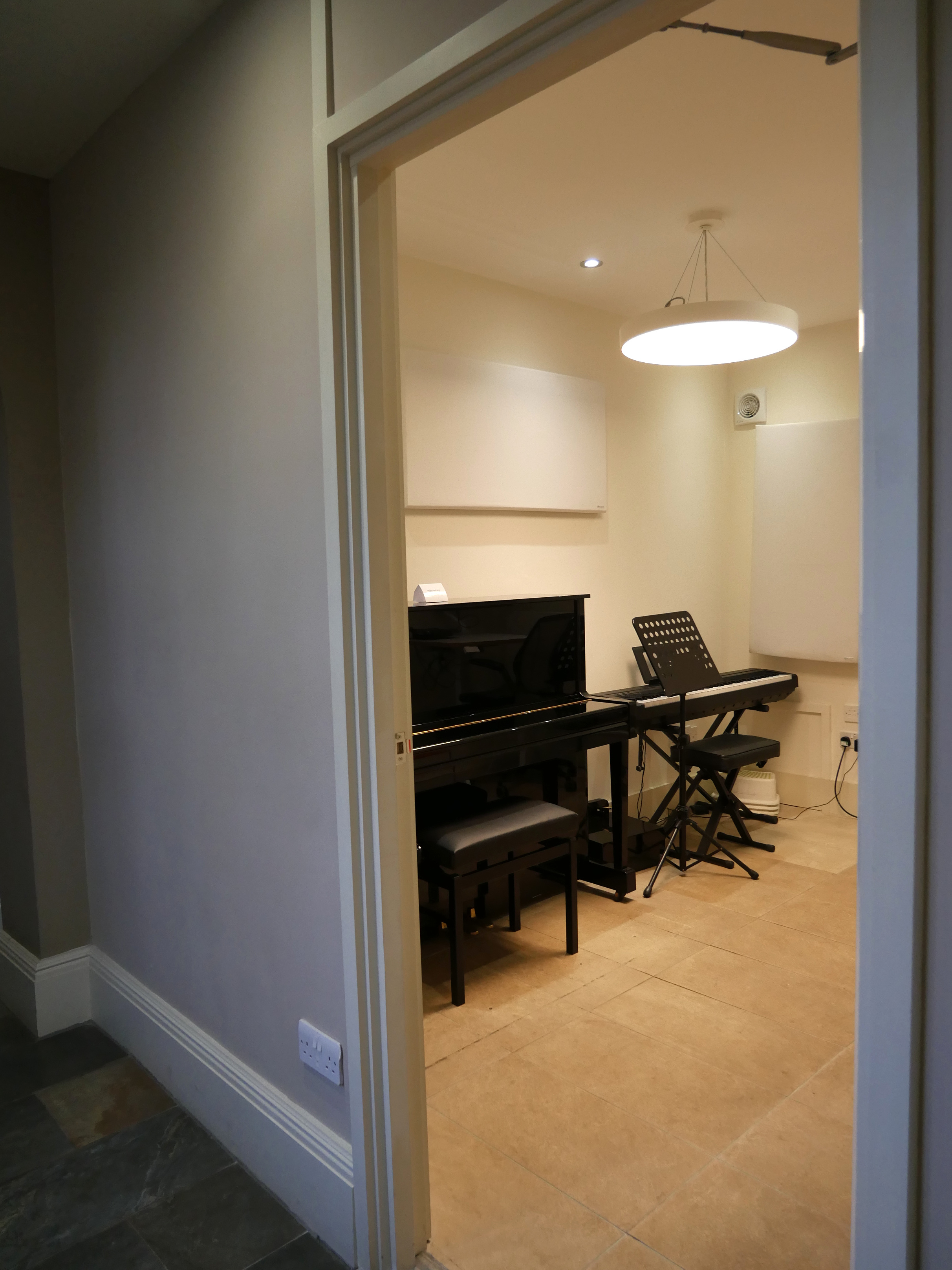 A finished teaching room at The Stables containing an upright piano and an electronic keyboard.