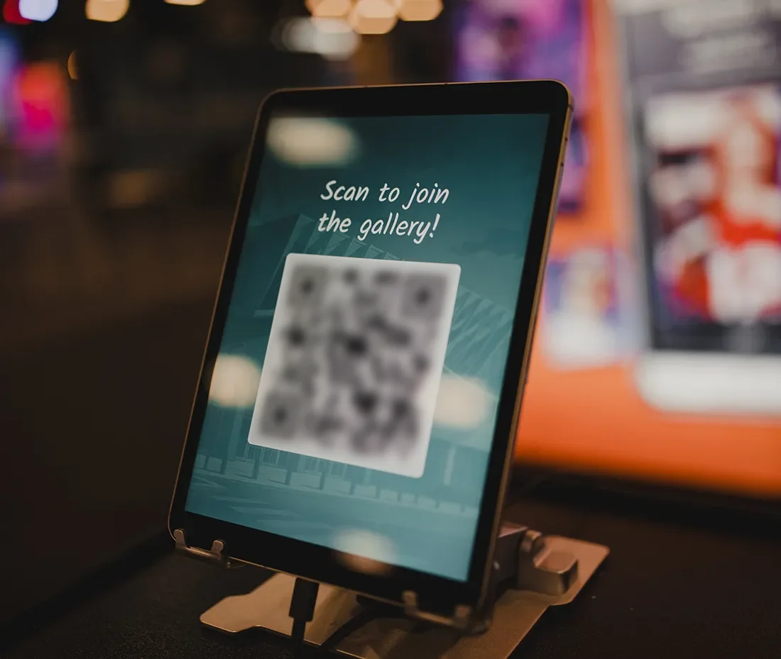 ipad screen with a qr code instructing attendees to scan it to join the gallery and access the photo booth