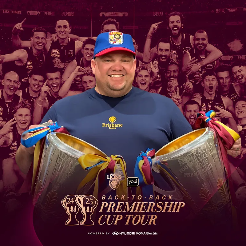 Photo booth snapshot of a fan holding two trophies on a Brisbane Lions Back to Back Premiership Cup Tour frame