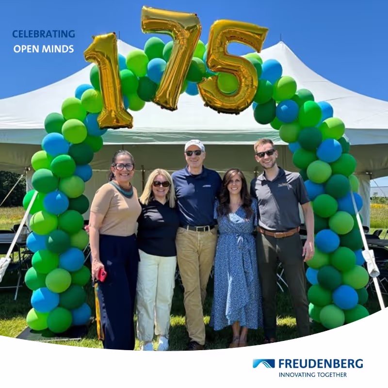 Photo booth snapshot of five guests under a 175 balloon arch on a Freudenberg Celebrating Open Minds frame