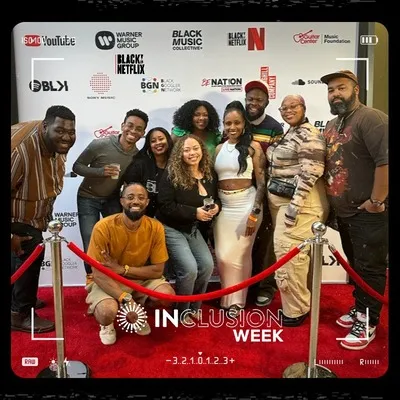 Photo booth snapshot of a group on a red carpet Inclusion Week frame with Warner Music and Netflix branding