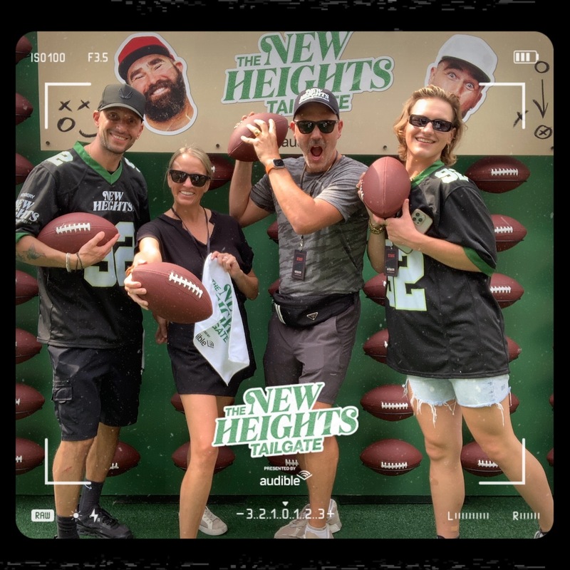 Photo booth snapshot of four fans holding footballs at the New Heights Tailgate presented by Audible