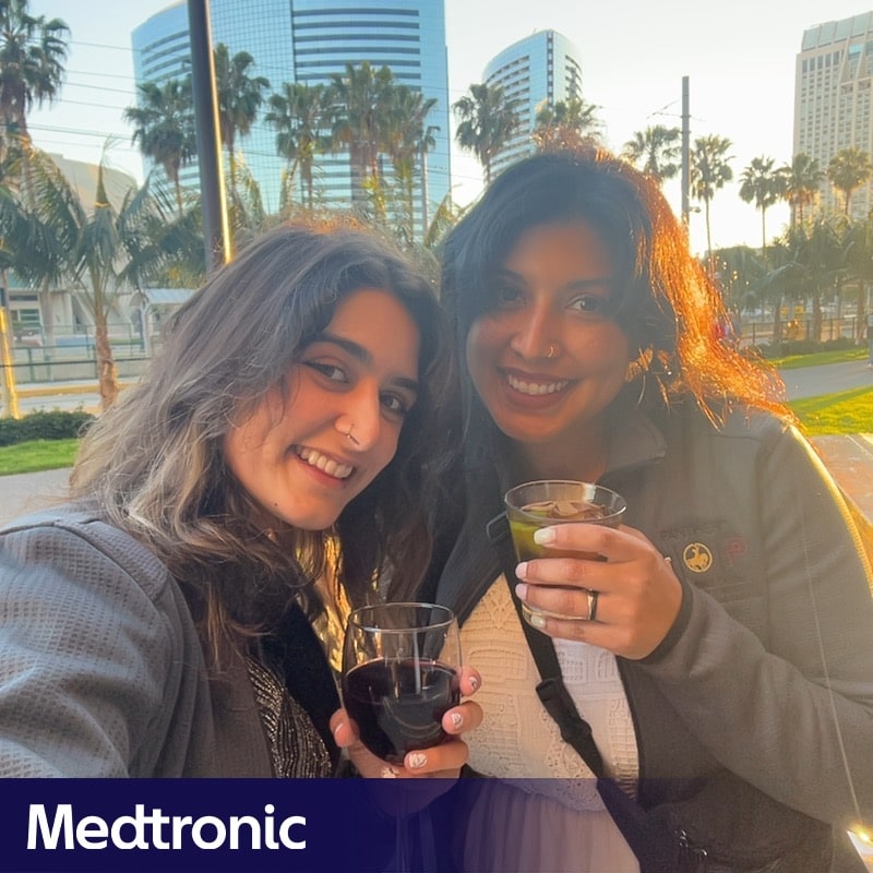 Photo booth snapshot of two guests with drinks at sunset on a Medtronic frame