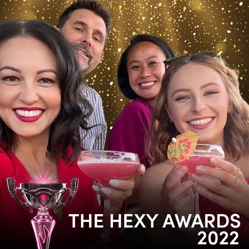 Photo booth snapshot of four guests raising pink cocktails on a gold Hexy Awards 2022 frame