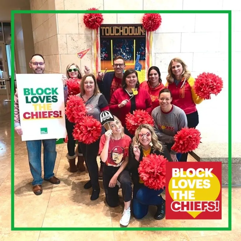 Photo booth snapshot of a team with red pom poms on an H&R Block Loves the Chiefs frame