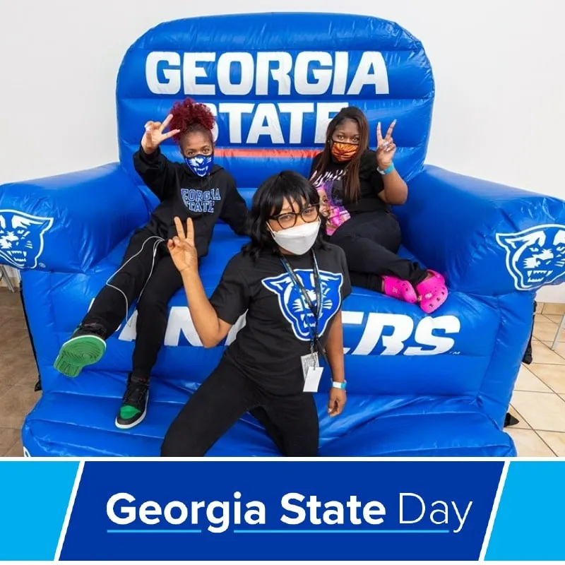 Photo booth snapshot of three kids on a giant inflatable Georgia State chair on a Georgia State Day frame