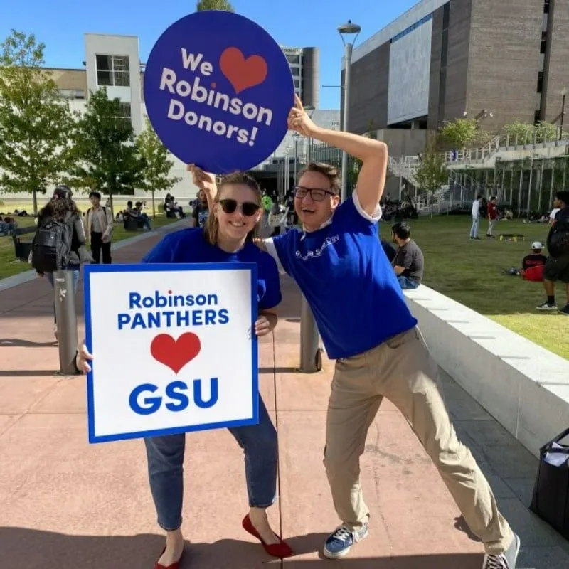 Photo booth snapshot of two guests holding We Love Robinson Donors signs on a GSU campus