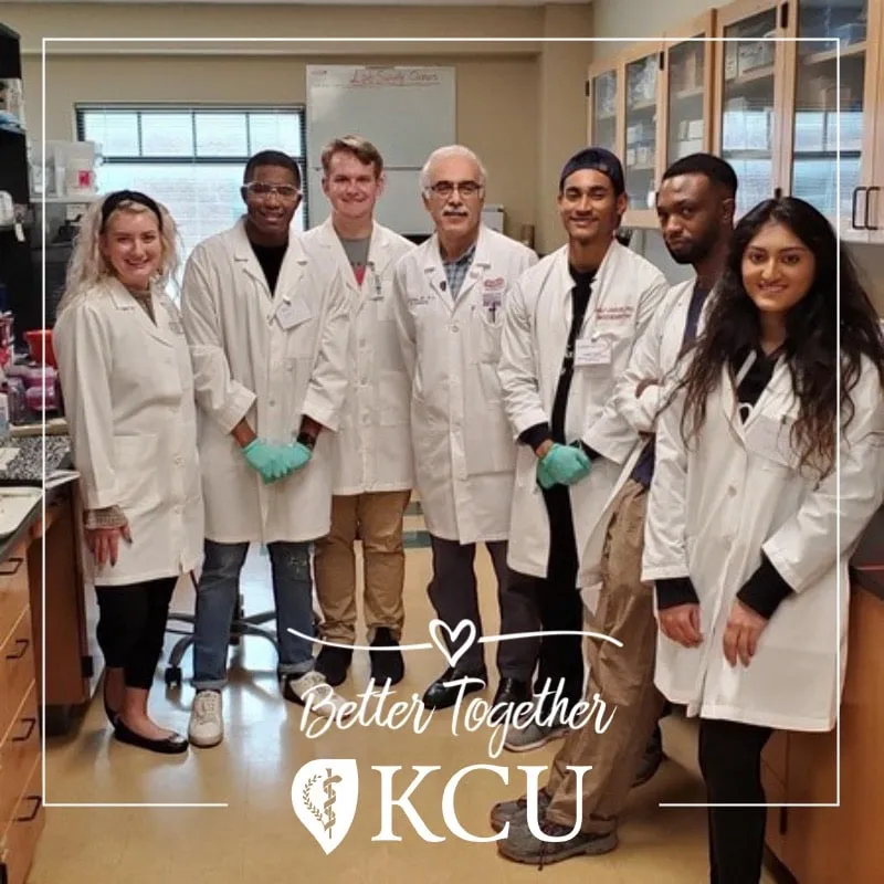 Photo booth snapshot of seven researchers in lab coats on a KCU Better Together frame